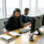 Call center agents handling customer inquiries at modern office desks, focused and professional.